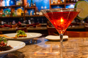martini next to plates of food at bar