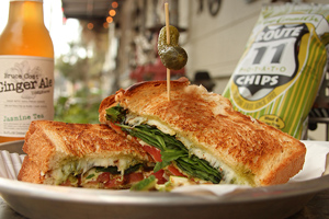 closeup of caprese sandwich in front of Ginger Ale and bag of chips