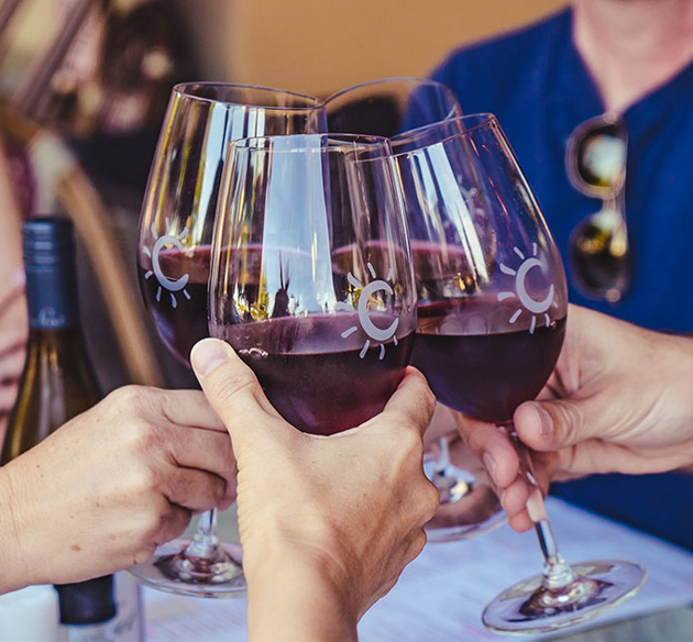 hands of four people clinking wine glasses