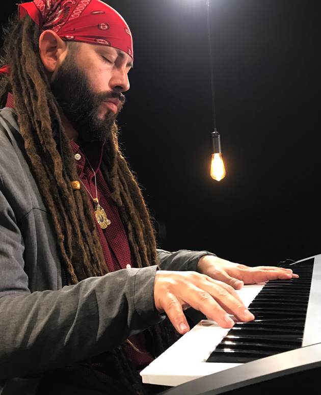 man with dreadlocks playing keyboard