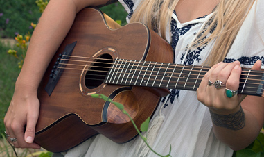 woman holding small brown acoustic guitar